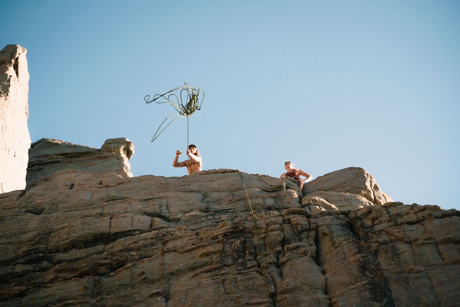 Two rock climbers engage with ropes on a sunlit cliff, epitomizing adventure.